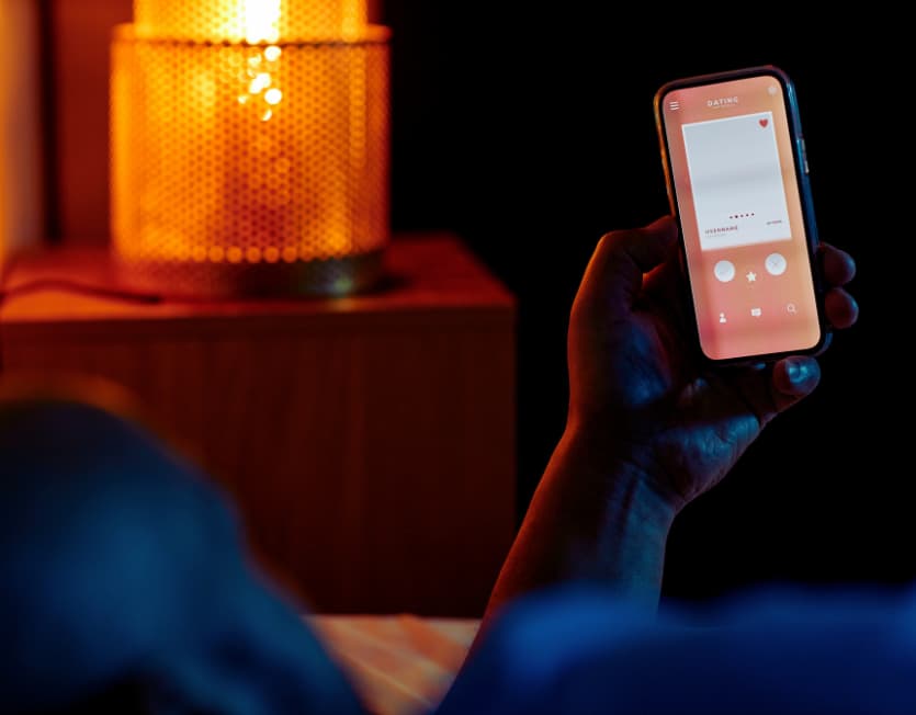Hand hält Smartphone mit geöffneter Dating-App im warmen Abendlicht