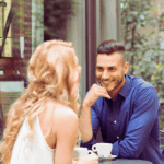 Mann und Frau beim ersten Date in einem Café, beide lächeln und lehnen sich leicht zueinander – positive Körpersprache beim Dating.