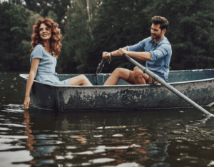 Ein Mann rudert mit einer Frau in einem Boot auf einem ruhigen See – ein romantischer Moment, der zeigt, dass Frauen erobern lernen auch mit Authentizität, Charme und echter Verbindung möglich ist.