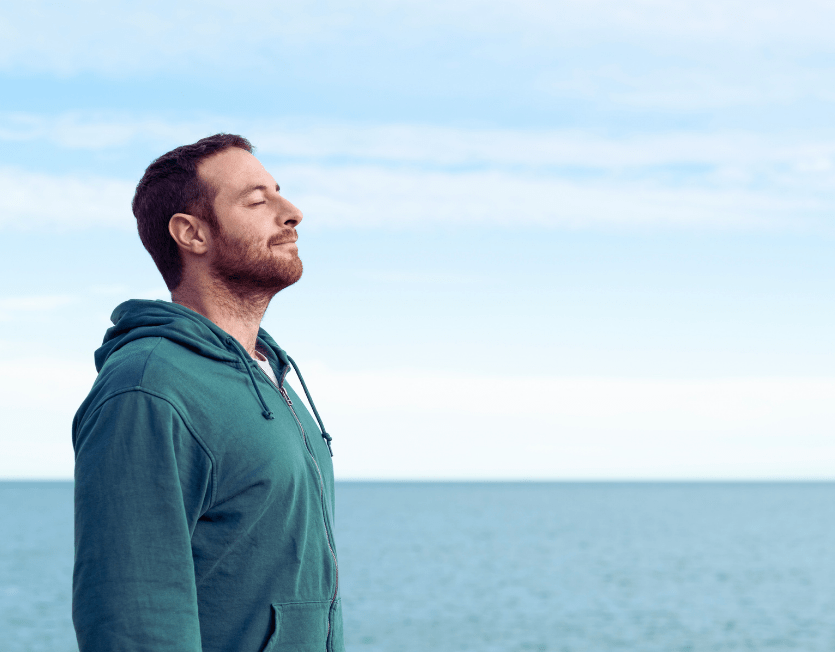 Bewusst leben – Mann macht Atemübung am Meer für Präsenz und Selbstbewusstsein